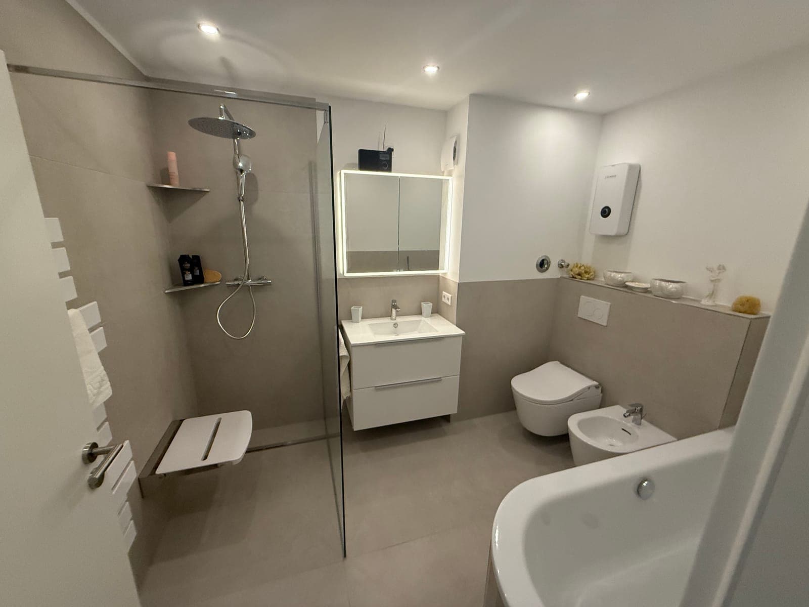 Badezimmer mit bodengleicher Dusche, Badewanne und Wand-WC