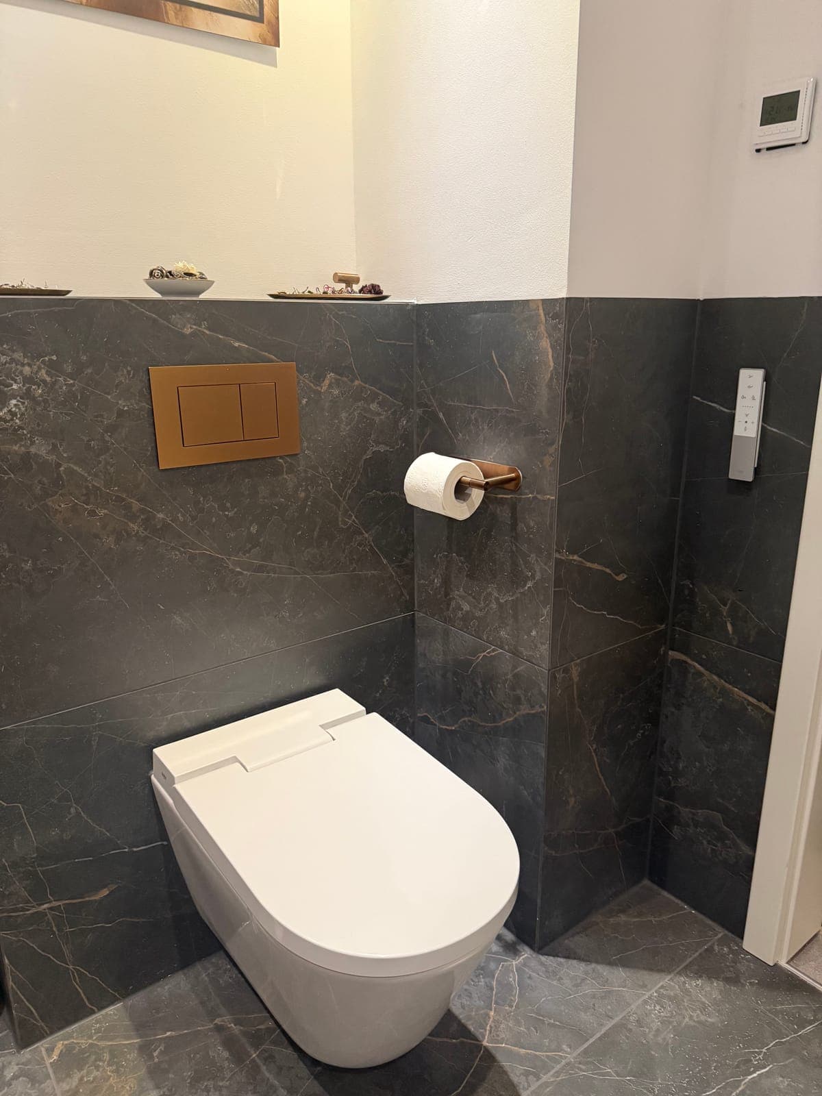 Wand-WC vor großformatiger Wandverkleidung in dunkler Steinoptik