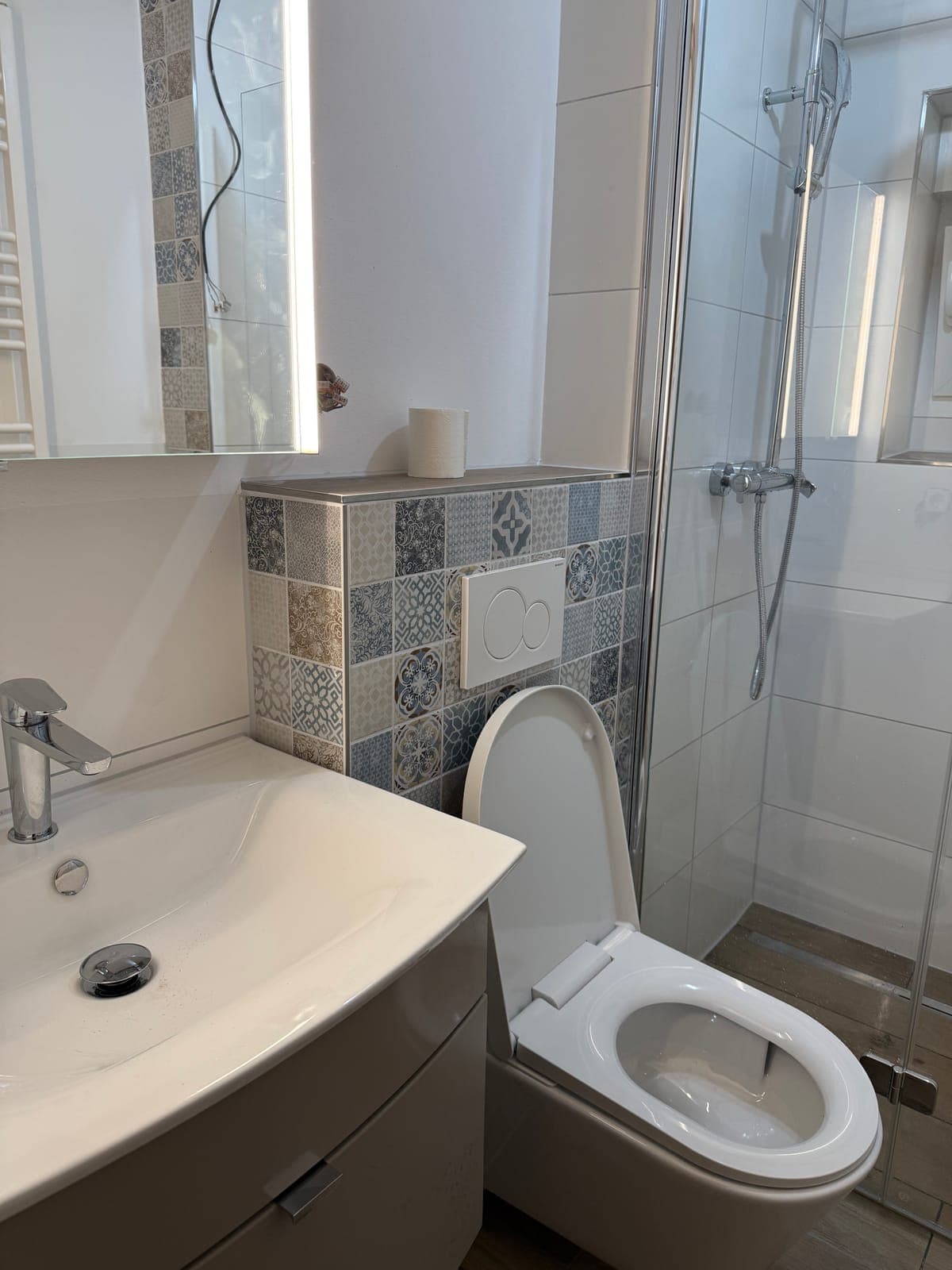 Kleines Bad mit Waschtisch, WC und Dusche mit Mosaikfliesen