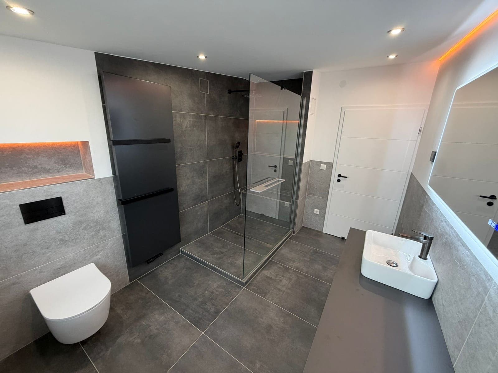 Badezimmer mit Wand-WC, Glasdusche und indirekter Beleuchtung