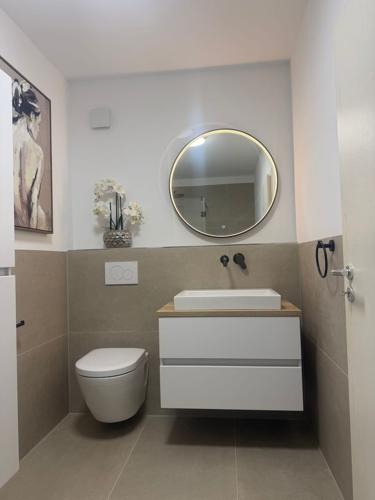 Gäste-WC mit rundem Spiegel und wandhängendem Waschtisch