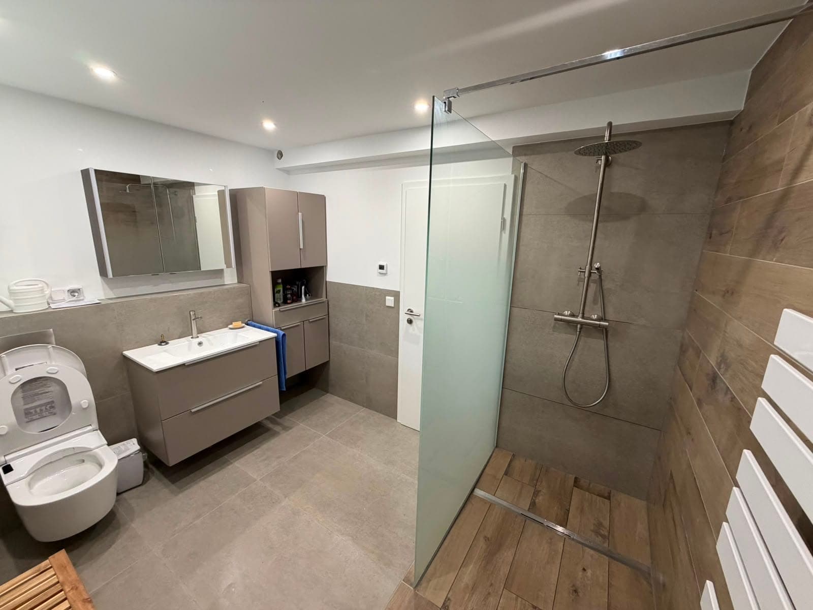 Badezimmer mit Waschtisch, WC und Dusche in Holz- und Steinoptik